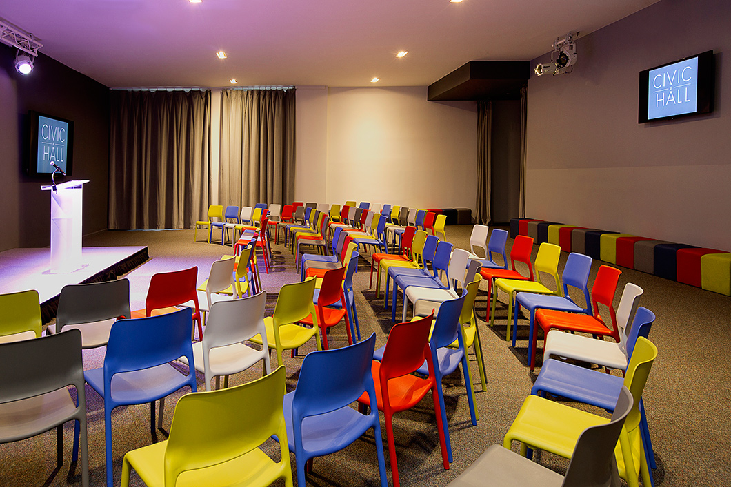 Lightweight stacking chairs and modular ottomans provide maximum flex for a multipurpose space that hosts lectures, receptions, workshops and movies on near-daily regular basis. The bright palette adds a blast of energetic color. | Featured: Spark Series Side Chairs, k. lounge Stools